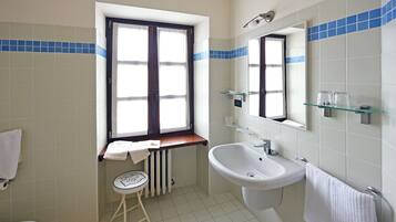A bathroom with a toilet, sink, and window.