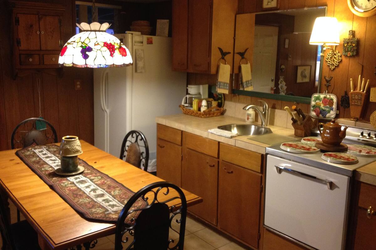 Eine kleine Küche mit Holzausstattung, einem weißen Kühlschrank, einer Spüle und einem Herd.