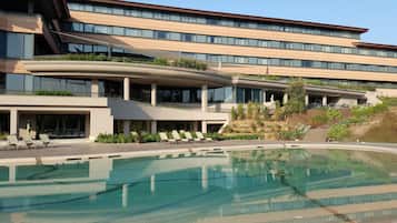 Un hotel moderno con una piscina amplia, varios balcones y un jardín ajardinado.