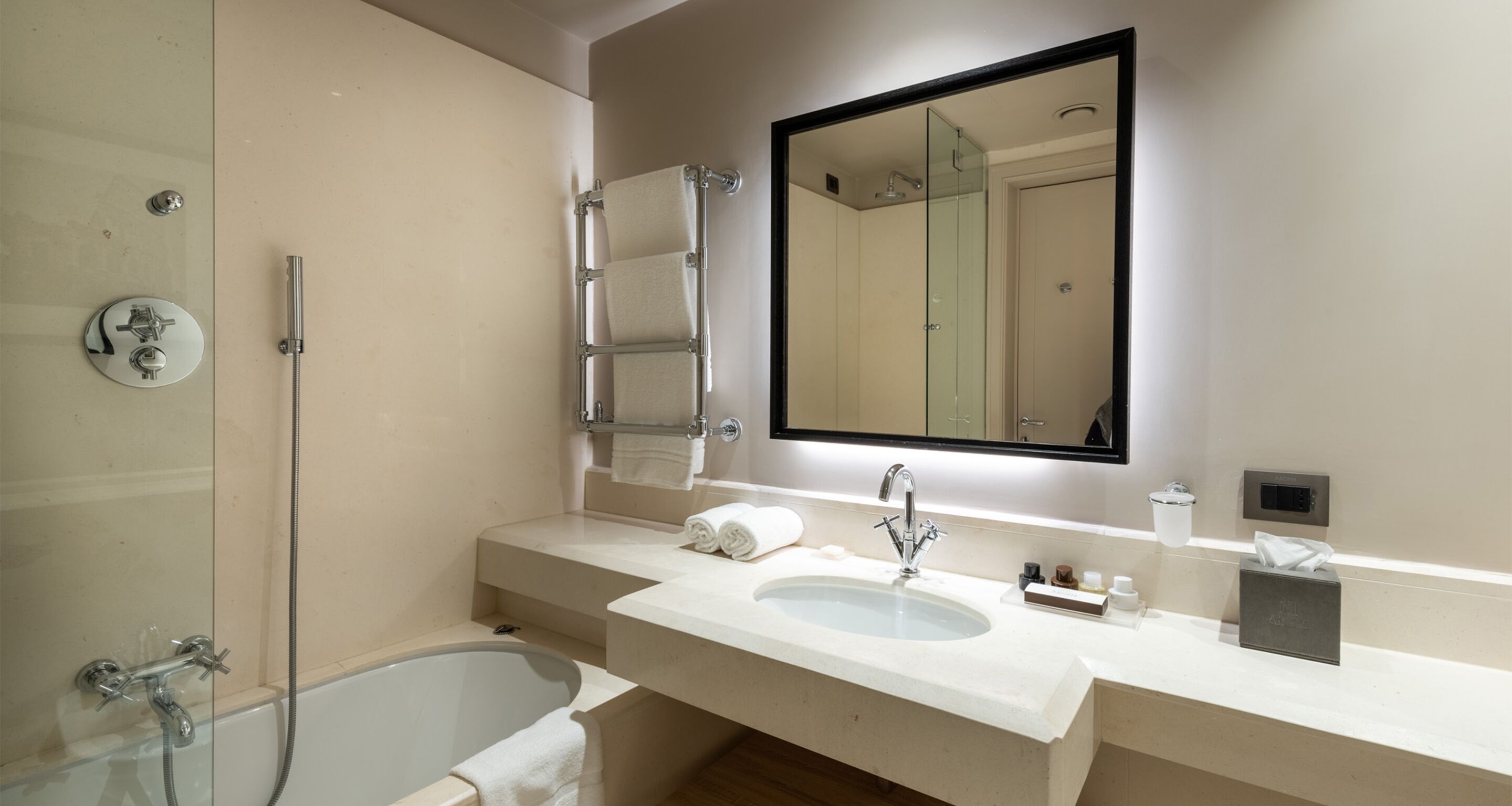 A modern bathroom with a glass-enclosed shower, a large sink with a mirror above, and a toilet.