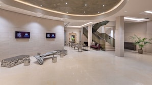 A spacious lobby with a curved ceiling, a staircase, and a seating area.
