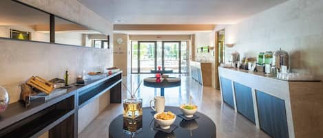Une cuisine moderne dotée d’un îlot central, d’un coin repas et offrant une vue sur l’espace piscine extérieur.