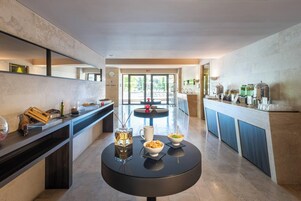 A modern kitchen with a central island, a dining area, and a view of the outdoor pool area.