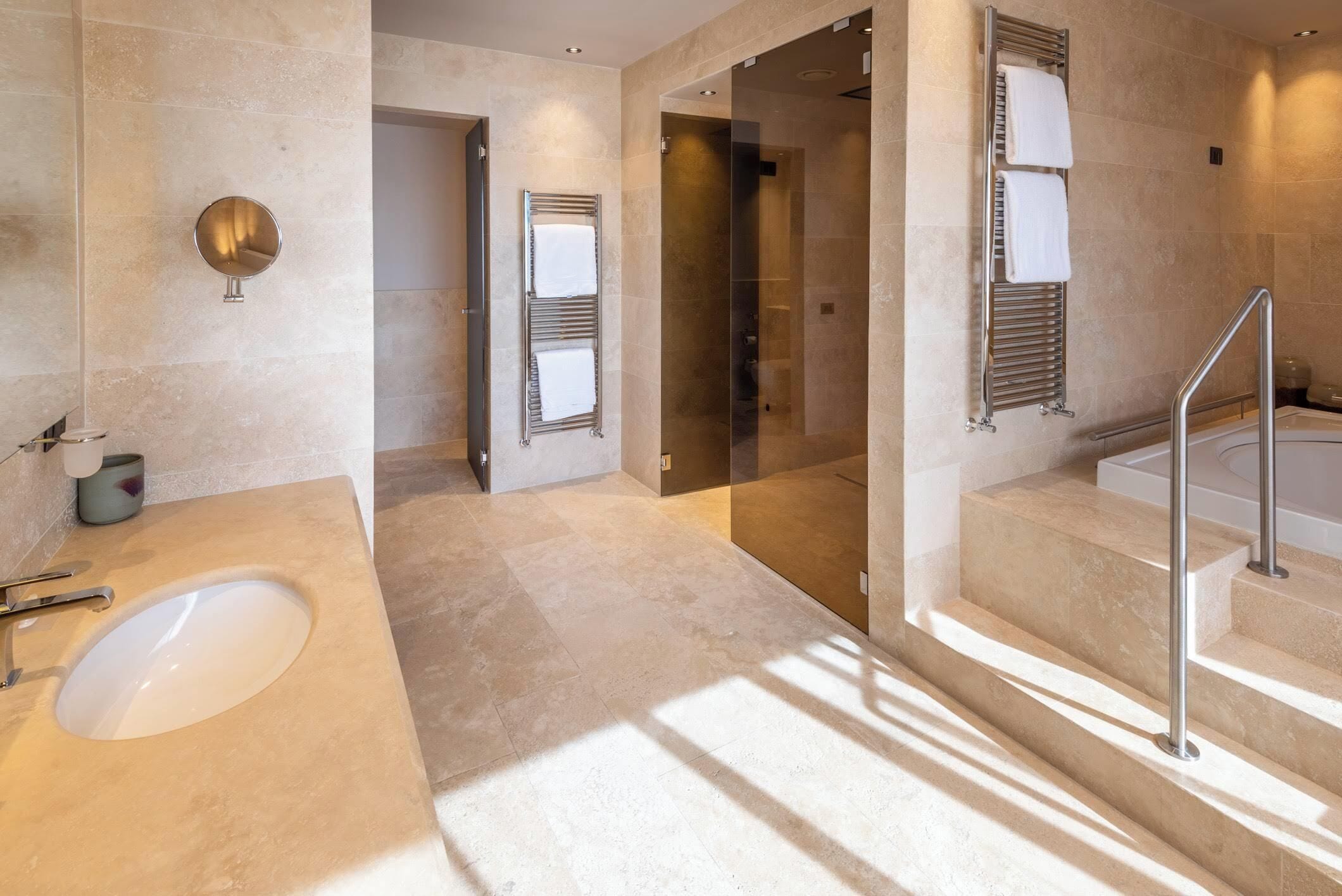 Une salle de bain moderne dotée d’un grand lavabo, d’une douche en verre et d’un escalier menant à un balcon.