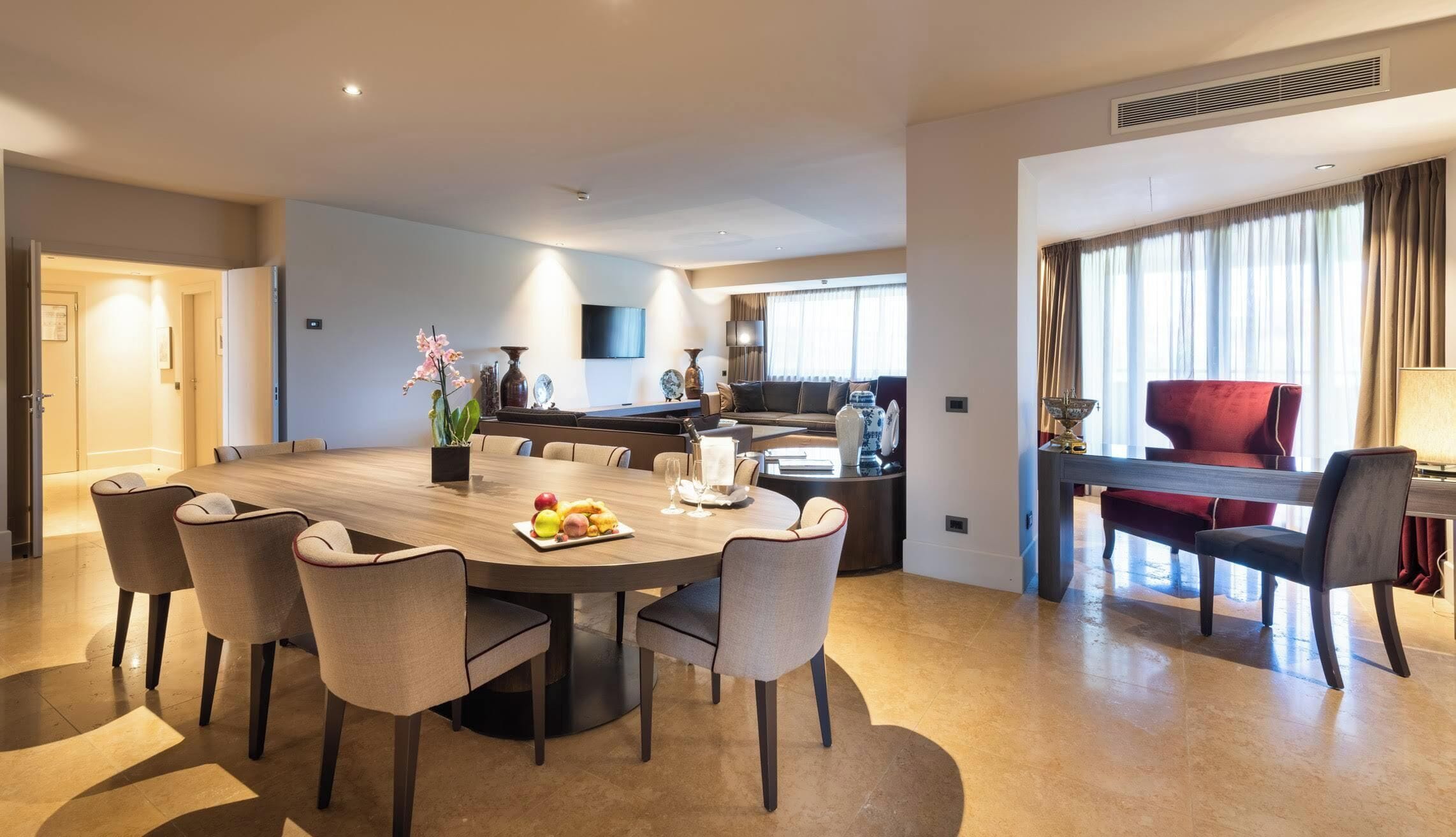 Quarto de hotel moderno com área de jantar, sala de estar e vista para a cidade.