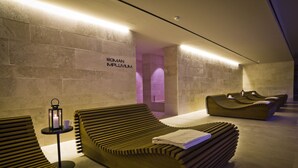 A modern spa area with wooden loungers, a small table with a lantern, and a sign reading "ROMAN IMPLVIVIUM".