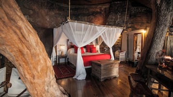 Ein rustikales Schlafzimmer mit einem Baldachinbett, Holzmöbeln und einem großen Baumstamm in der Ecke.