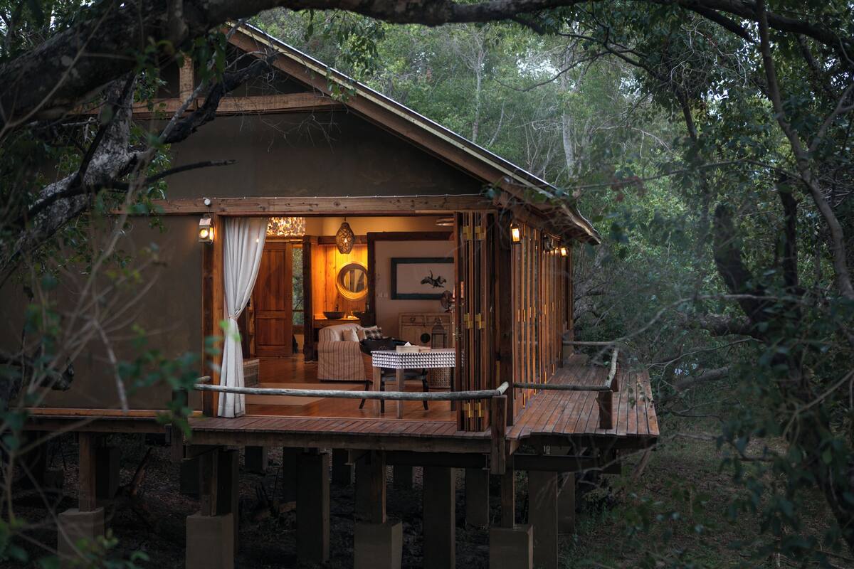 A wooden cabin with a balcony, a dining area, and a cozy interior with a fireplace.