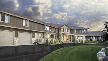 A modern two-story house with a stone facade, multiple garage doors, and a well-maintained lawn.