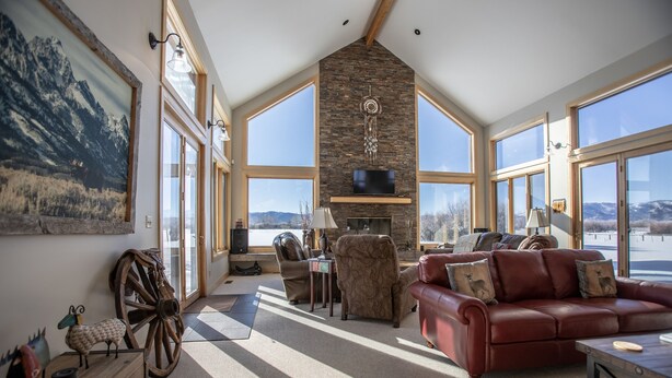 A spacious living room with a fireplace, large windows, and a view of the mountains. - Dreamcatcher Bed and Breakfast (Victor)