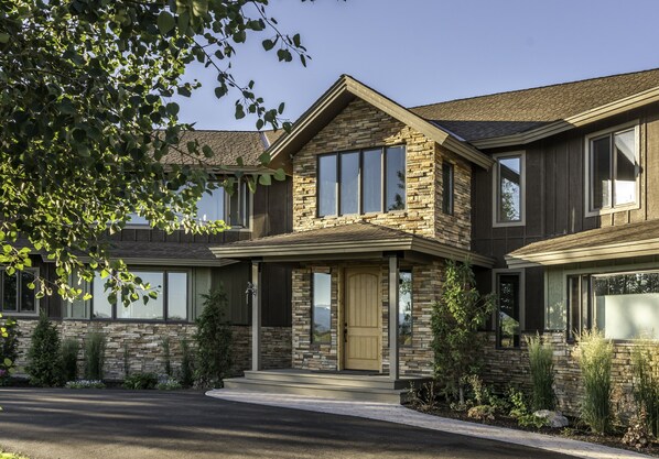 A two-story house with a stone facade, a front porch, and a driveway.