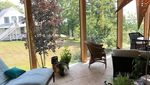 Une terrasse couverte avec un canapé, des fauteuils et des plantes en pot.
