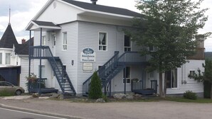 A two-story building with a sign reading "Residence de Tourisme" and a staircase leading to the second floor. - Les Appartements de la Bergeronnette (Les Bergeronnes)