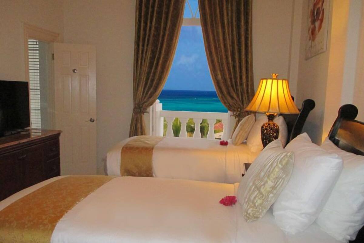 Een hotelkamer met twee bedden, een televisie en uitzicht op de oceaan.