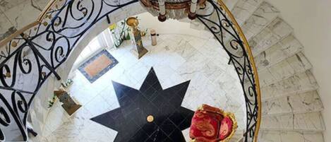 Una imponente escalera con un diseño de suelo en forma de estrella, un candelabro y barandillas decoradas.