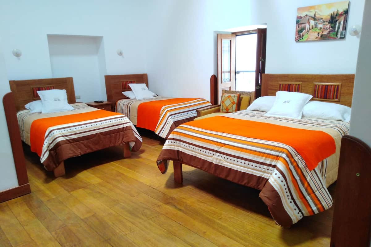 A hotel room with two single beds, wooden flooring, and a painting on the wall.