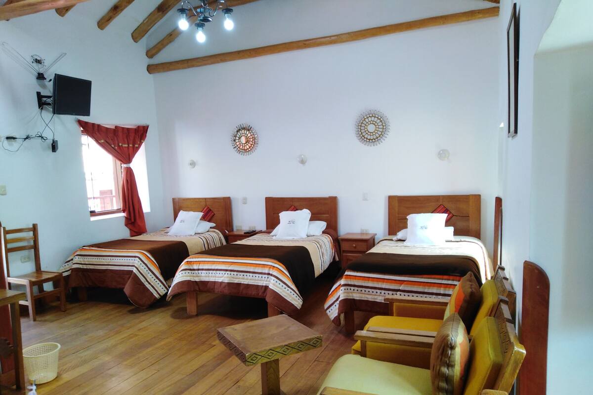 A hotel room with two beds, wooden furniture, and a television.