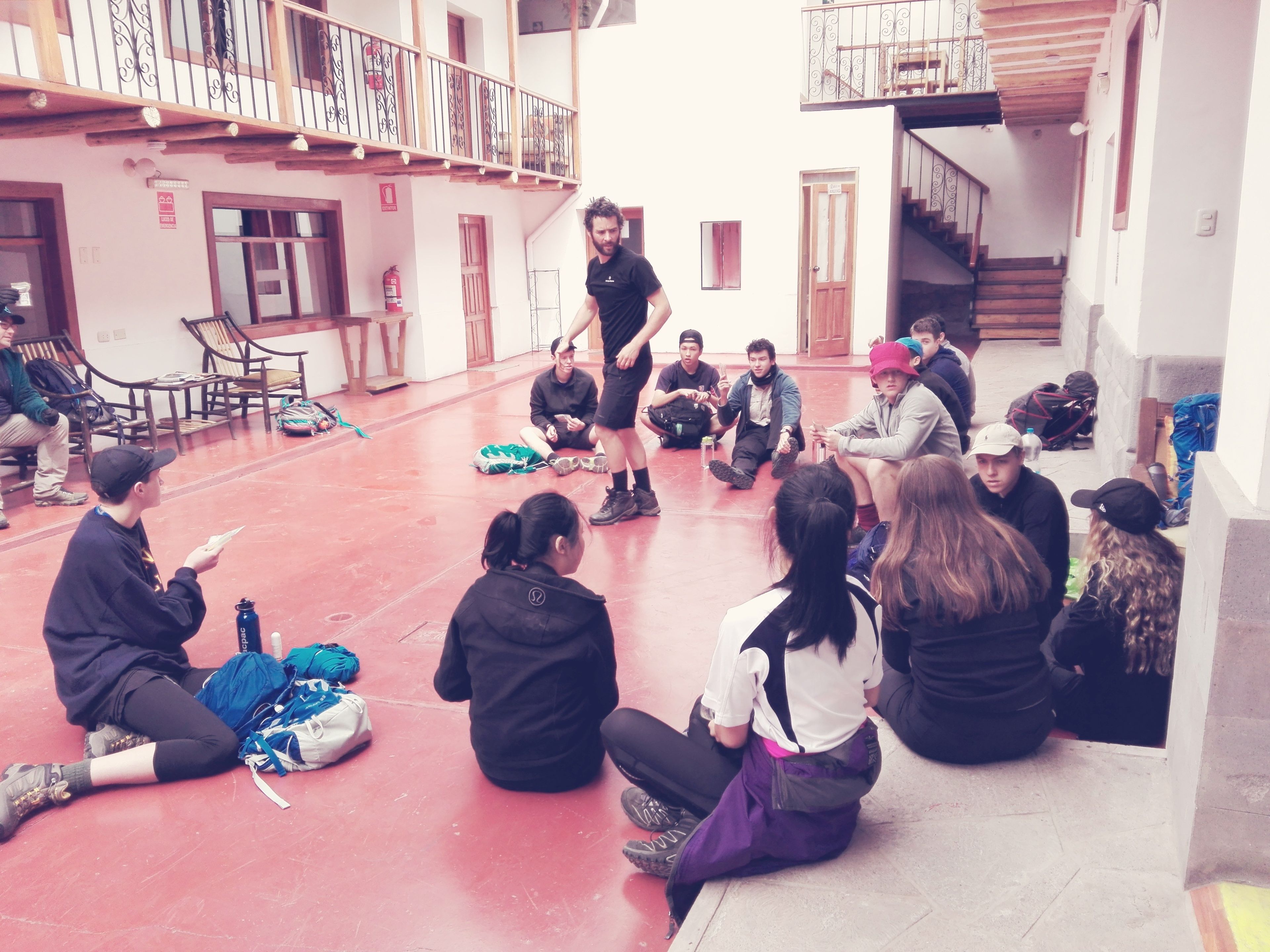 A group of people sitting in a courtyard with a building in the background.
