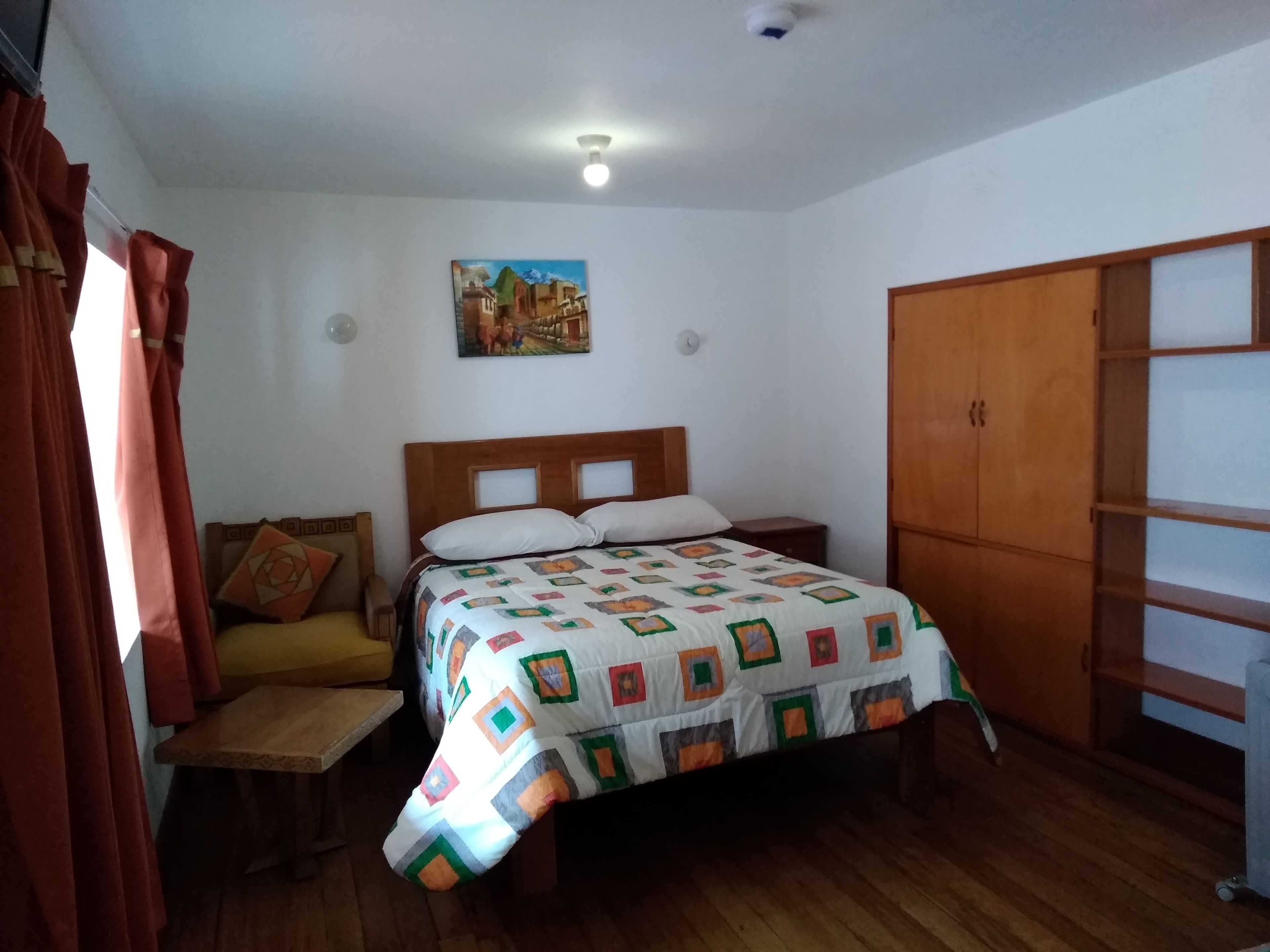 Une chambre à coucher avec un lit en bois, une table de chevet, une armoire en bois et un tableau accroché au mur.