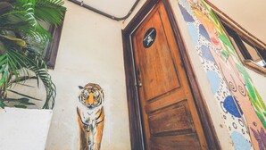Uma porta com um mural de tigre, moldura de madeira e uma parede com arte abstrata colorida.
