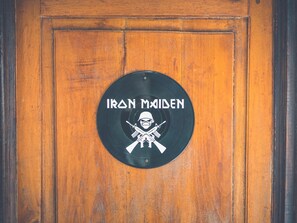 A wooden door with a circular plaque that reads "IRON MAIDEN" and features a skull and crossbones symbol. - Pura Vida Hostel (Tamarindo)