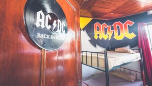 Uma cama de beliche com teto de madeira e uma parede com o logotipo grande da AC/DC.