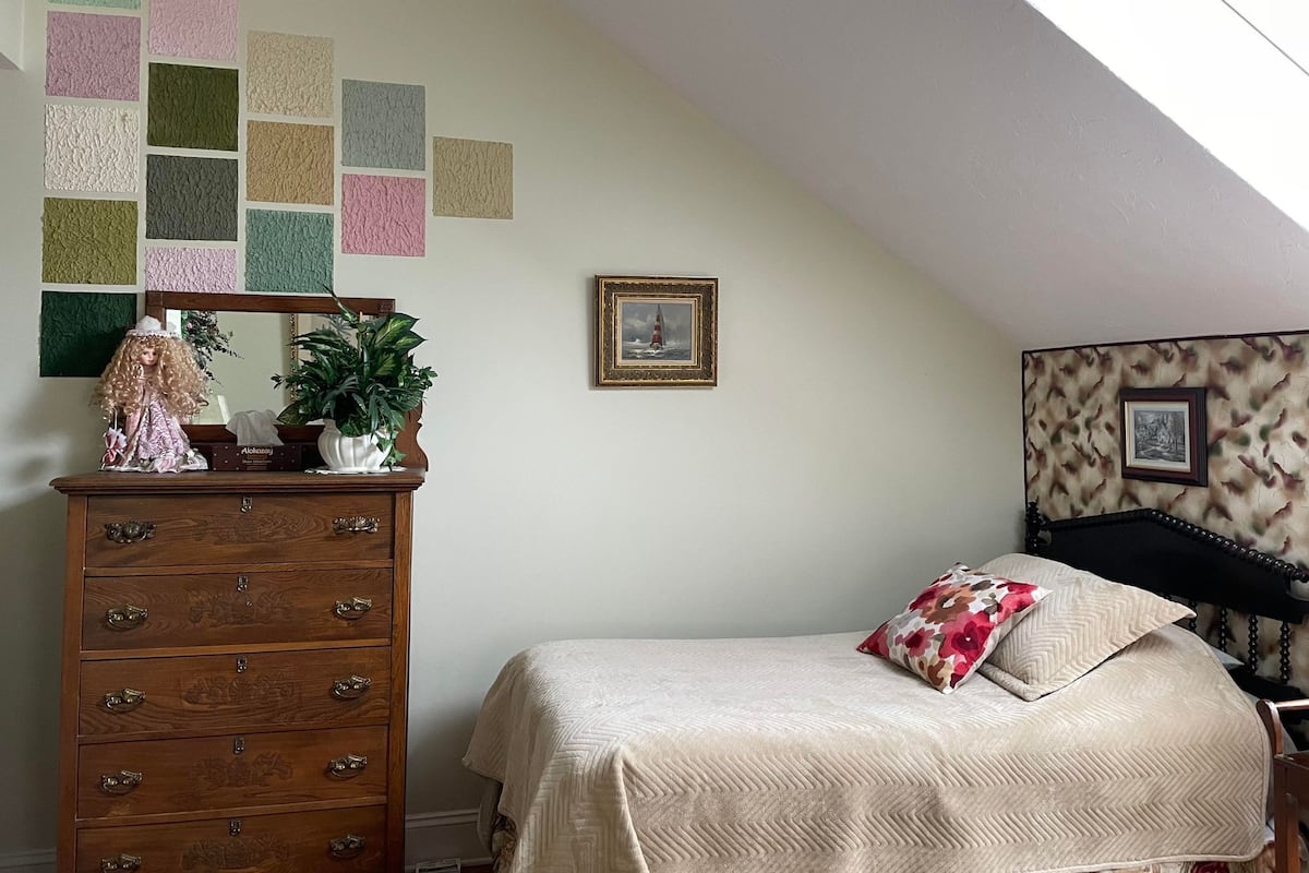 Un dormitorio con cama, cómoda, espejo y adornos en la pared.