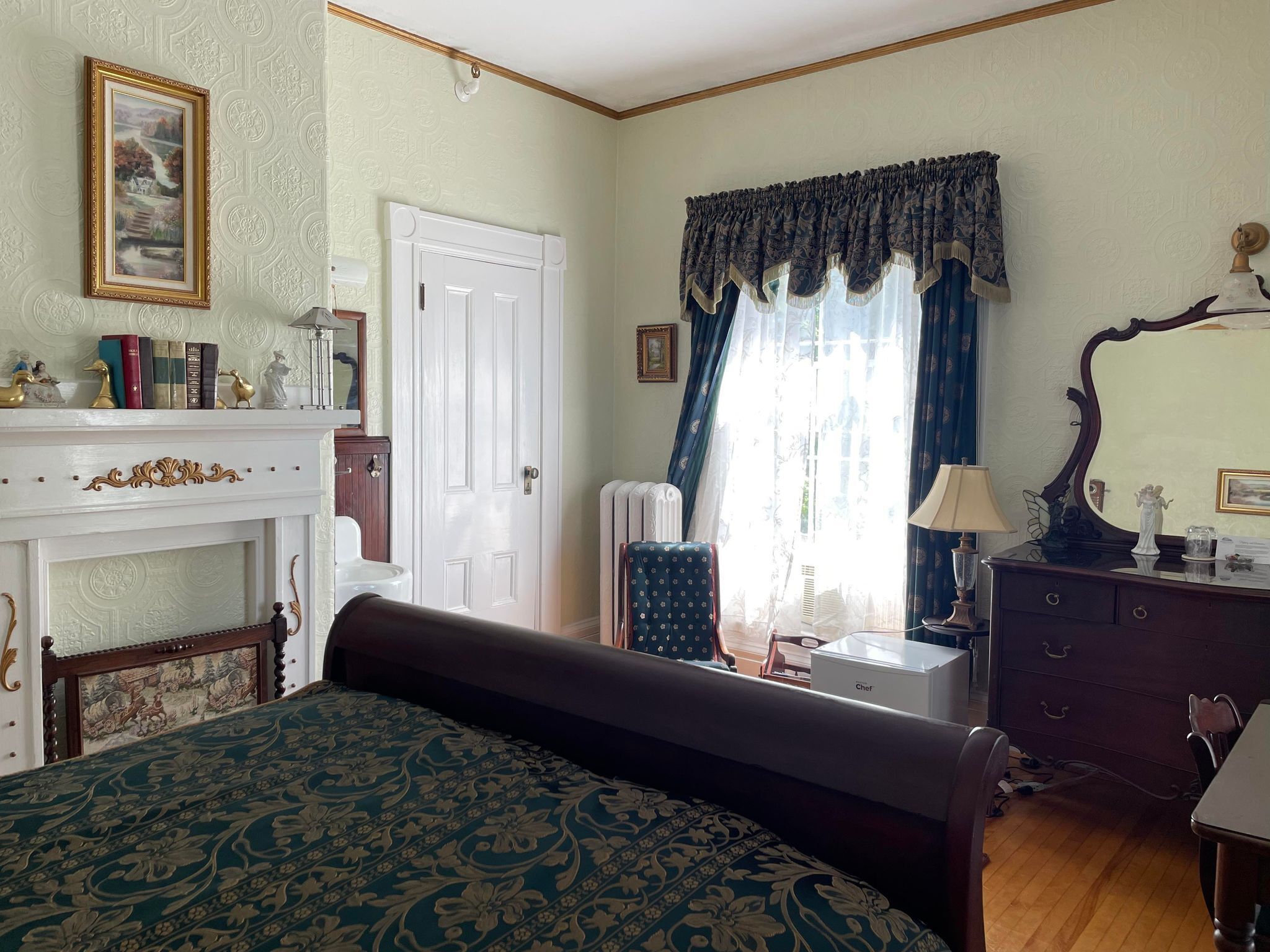Une chambre à coucher avec un grand lit, une commode, un miroir et une cheminée.