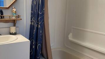 A bathroom with a bathtub, a sink, a mirror, and a shower curtain.