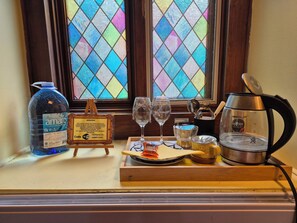Un equipo de minibar con una botella de agua, copas de vino, una cafetera y una bandeja.