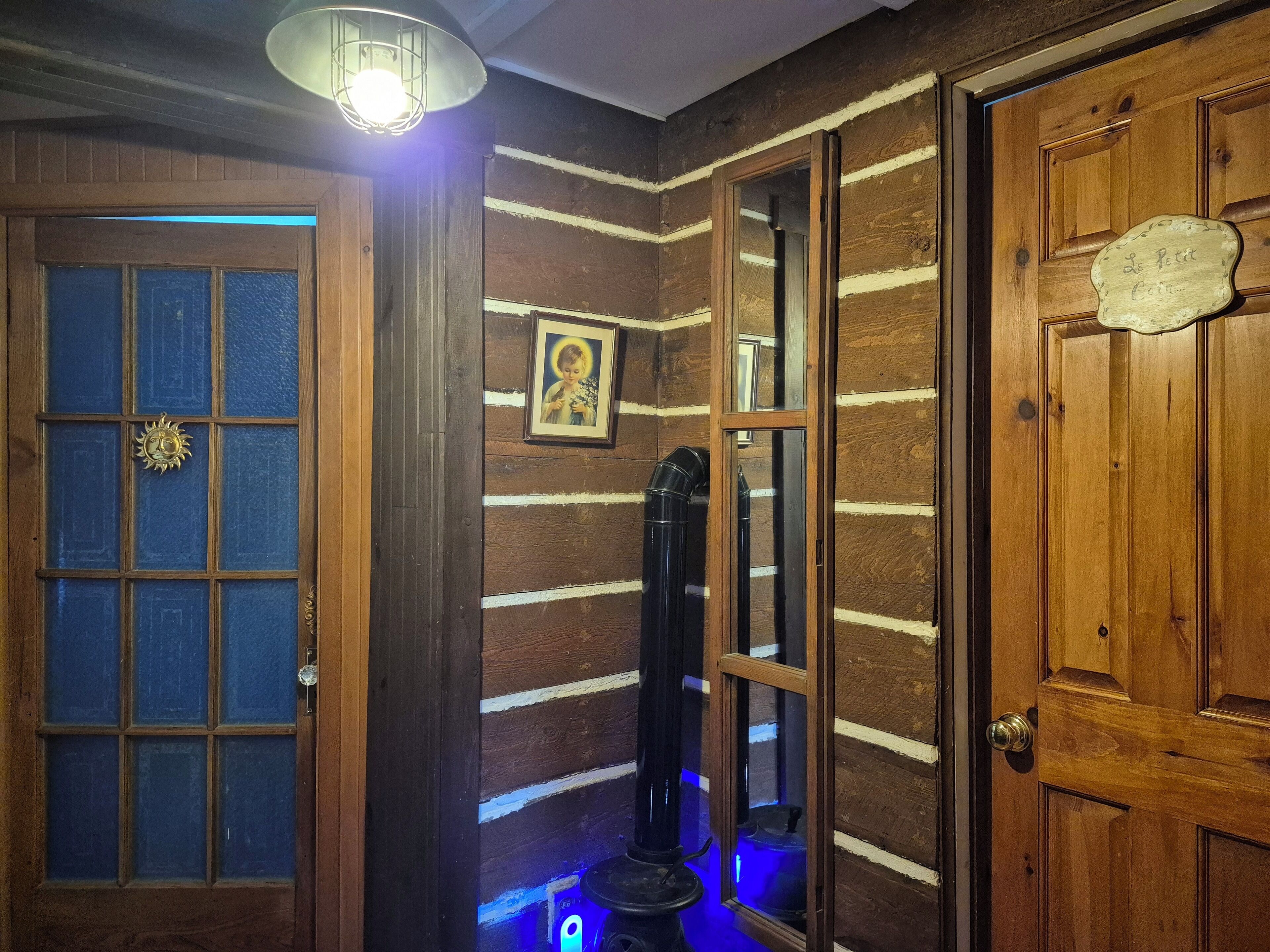 A wooden room with a door, a window, and a wall-mounted light fixture.