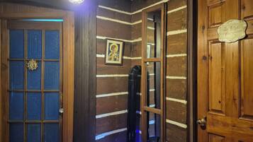 A wooden room with a door, a window, and a wall-mounted light fixture.