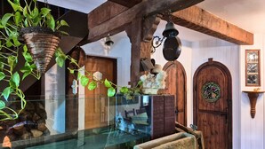 Un interior rústico con una puerta de madera, una vitrina de vidrio y plantas colgantes.