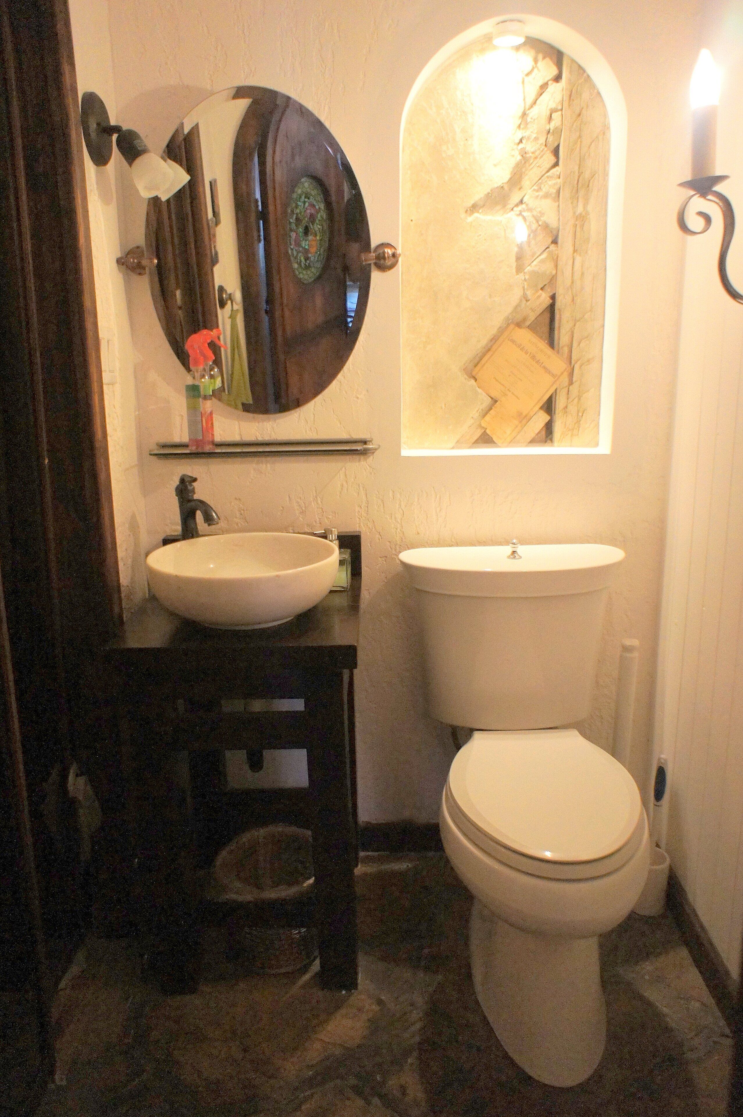 A bathroom with a round mirror, a sink, and a toilet.