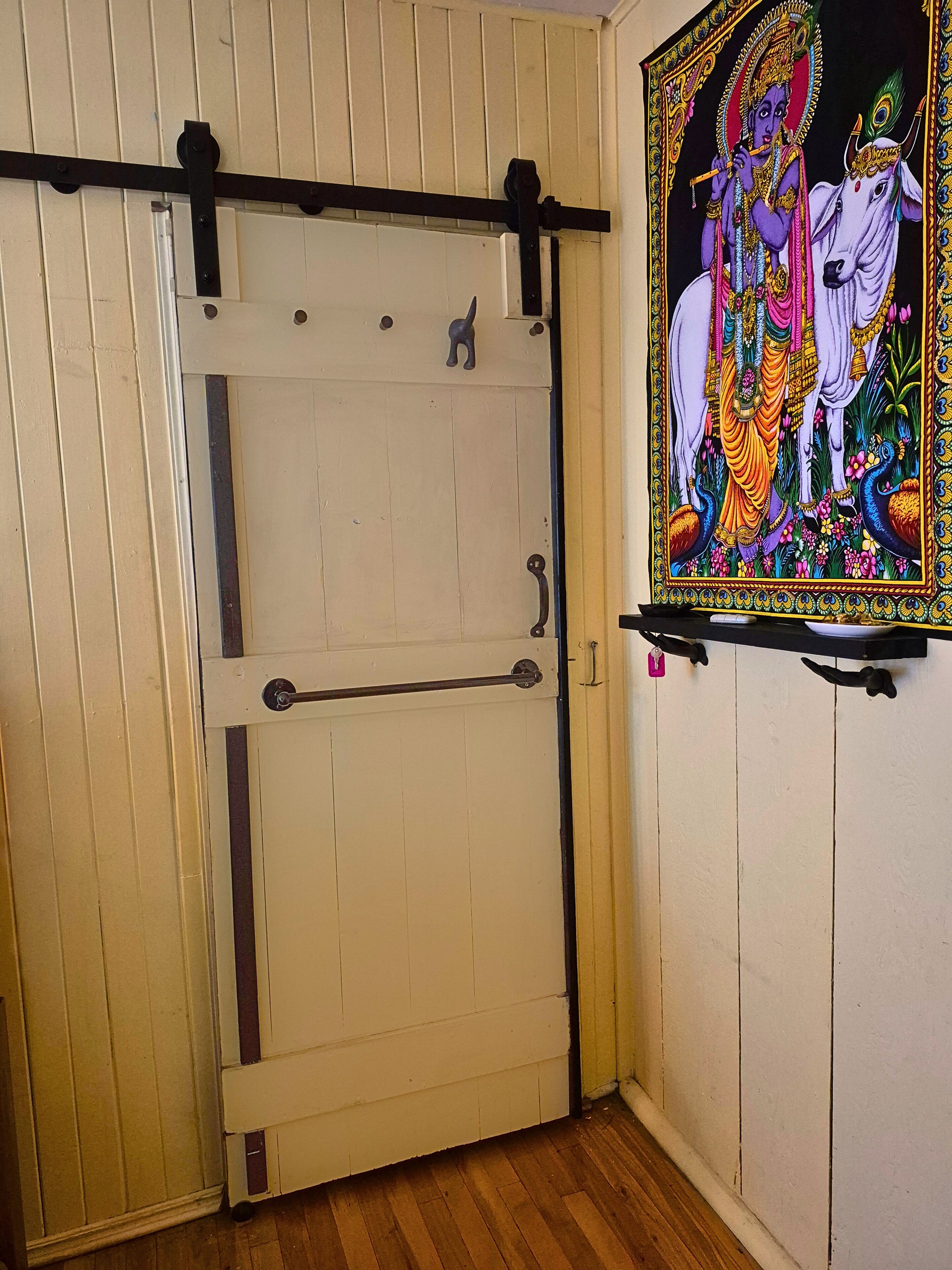Una habitación con puerta corredera, suelo de madera y un panel decorativo en la pared.