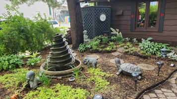 A garden with a spiral stone structure, various plants, and garden statues.