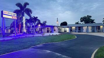 An American Inn with a simple motel structure, palm trees, and a well-maintained lawn.
