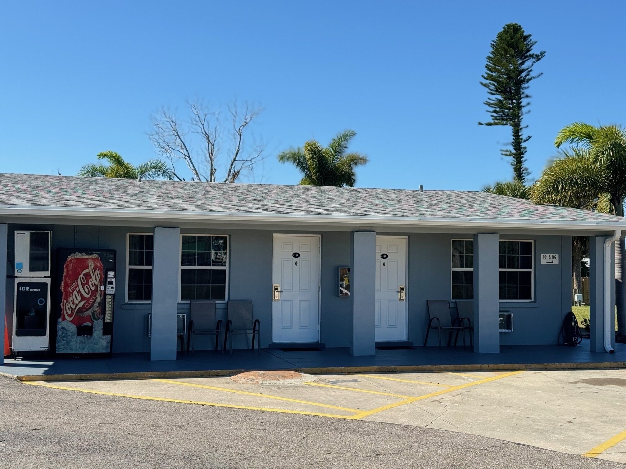 Un motel con una máquina expendedora de Coca-Cola, varias puertas y un estacionamiento.
