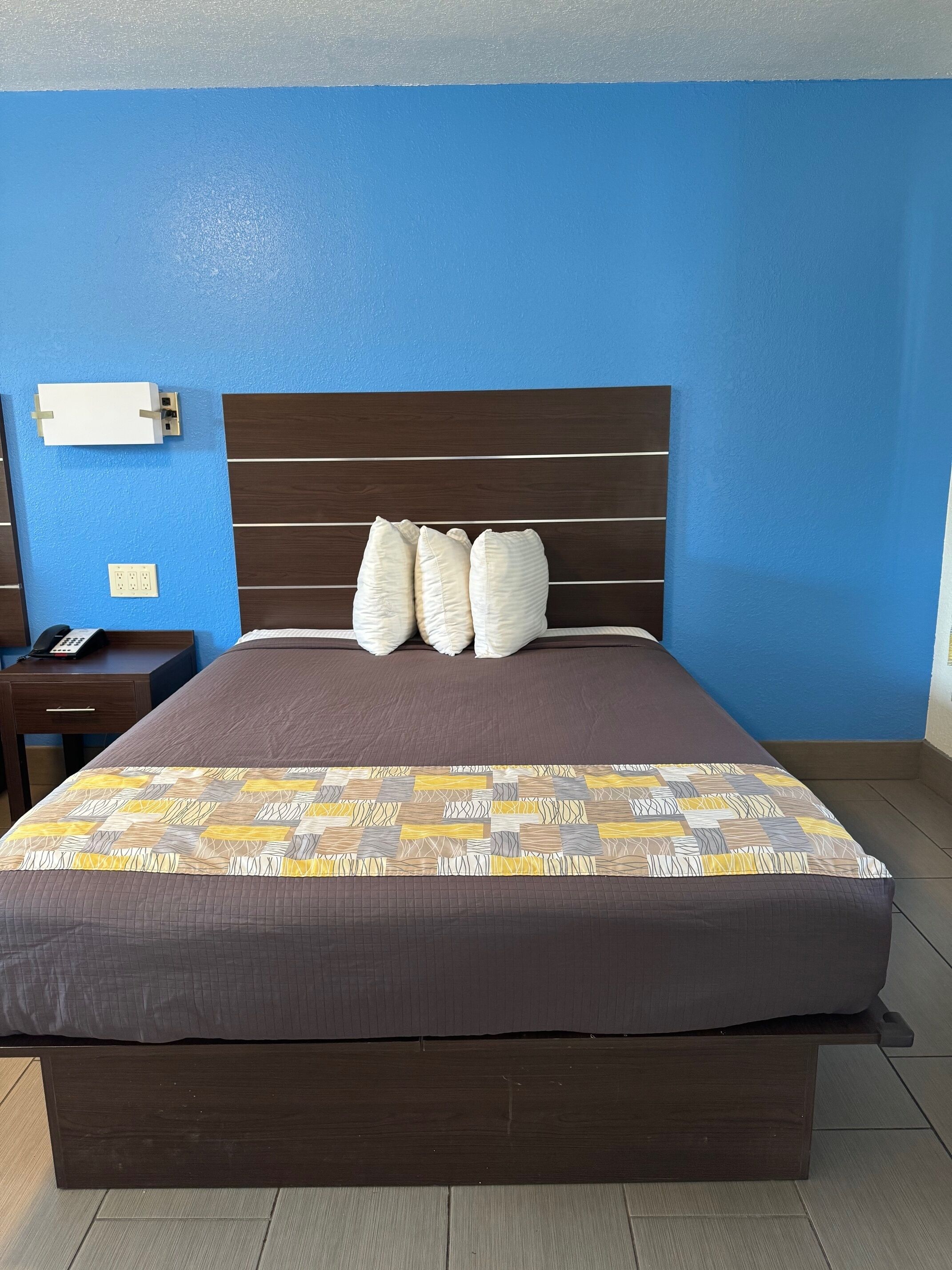 Una habitación de hotel con cama, mesita de noche y teléfono.