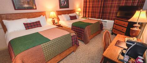A hotel room with two beds, a desk, a chair, a television, and a dresser.