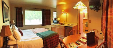 Una habitación de hotel con cama, escritorio, silla, televisor y ventana.