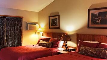Habitación de hotel con dos camas, una mesita de noche, una lámpara, un equipo de aire acondicionado y un cuadro en la pared.