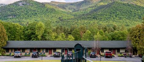 A motel with a playground, parking lot, and a mountain backdrop.