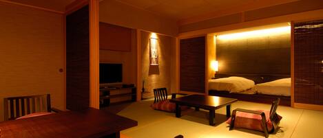 A traditional Japanese-style room with tatami flooring, a low table, and a television.