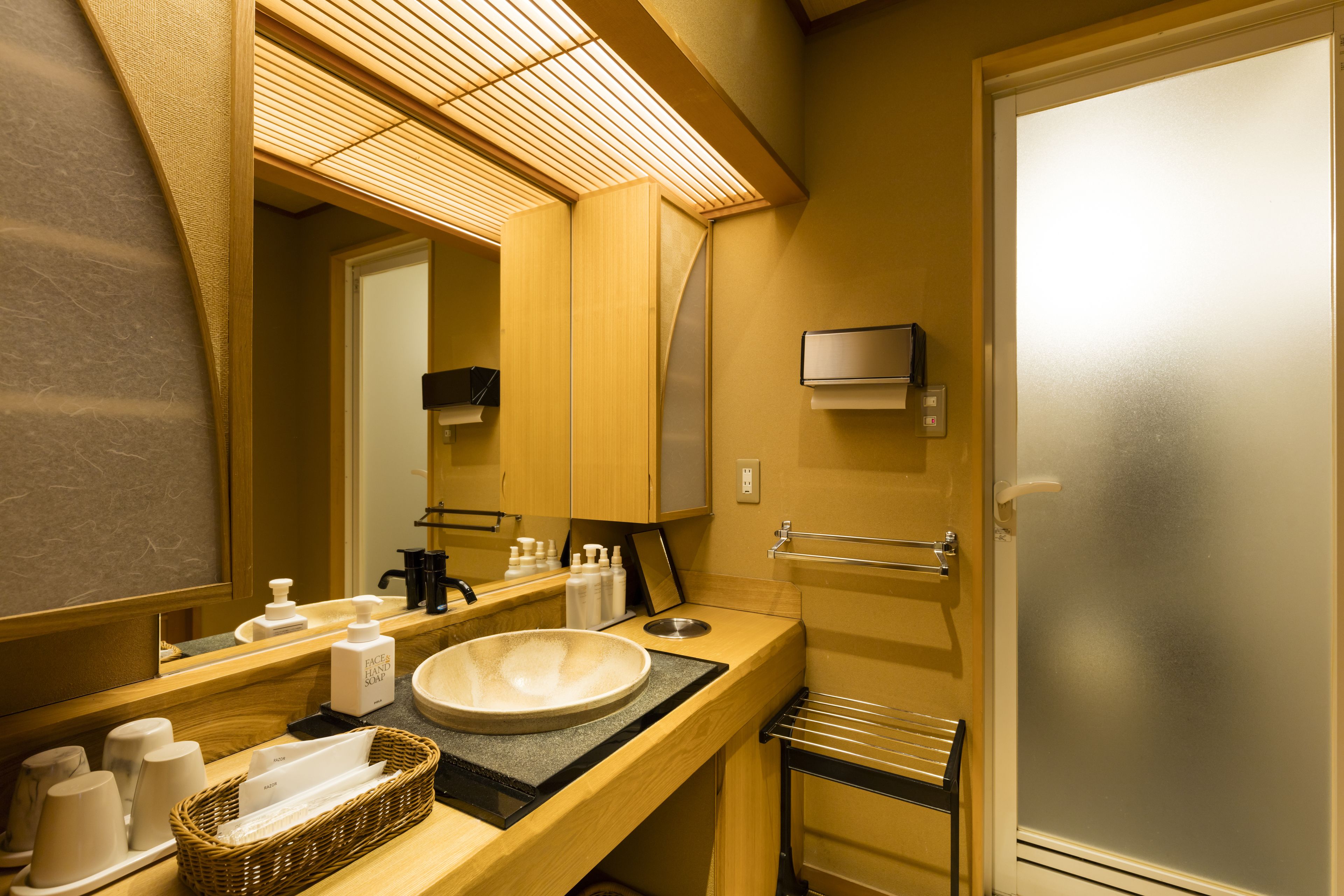 Un baño con tocador de madera, un espejo grande, un lavabo y un perchero para toallas.