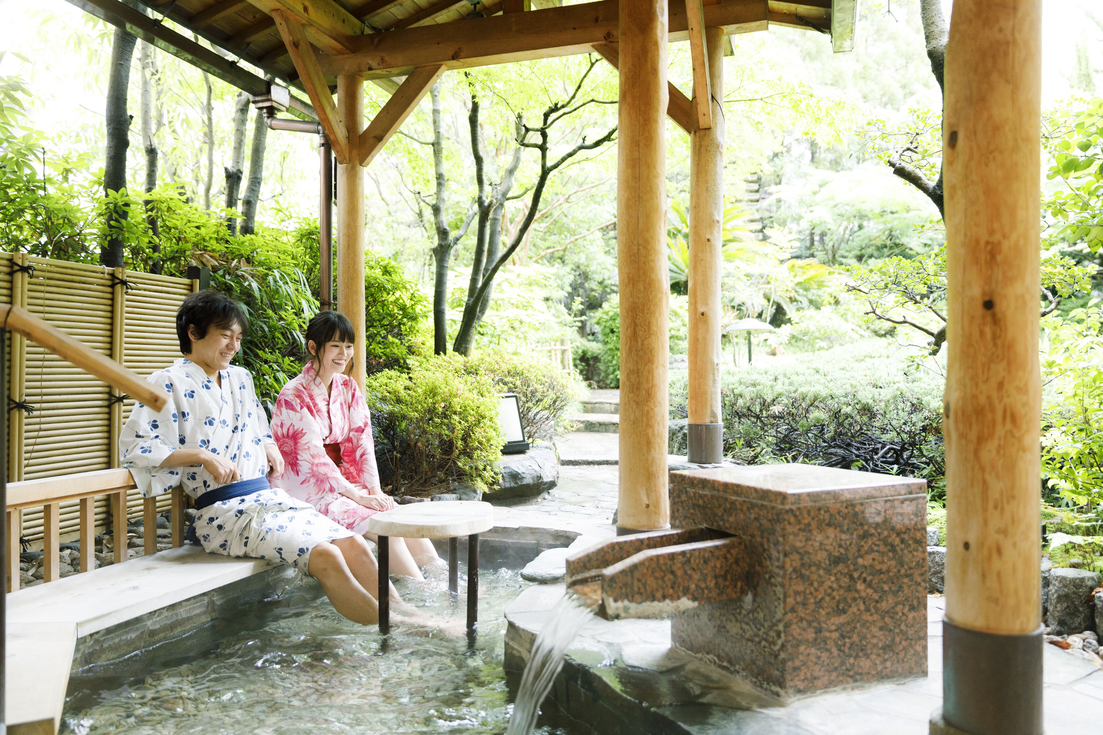 A traditional Japanese onsen with wooden structures and a natural garden setting.