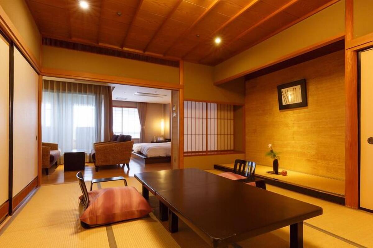 Ett traditionellt japanskt rum med tatamimattor på golvet, ett lågt bord och en säng.