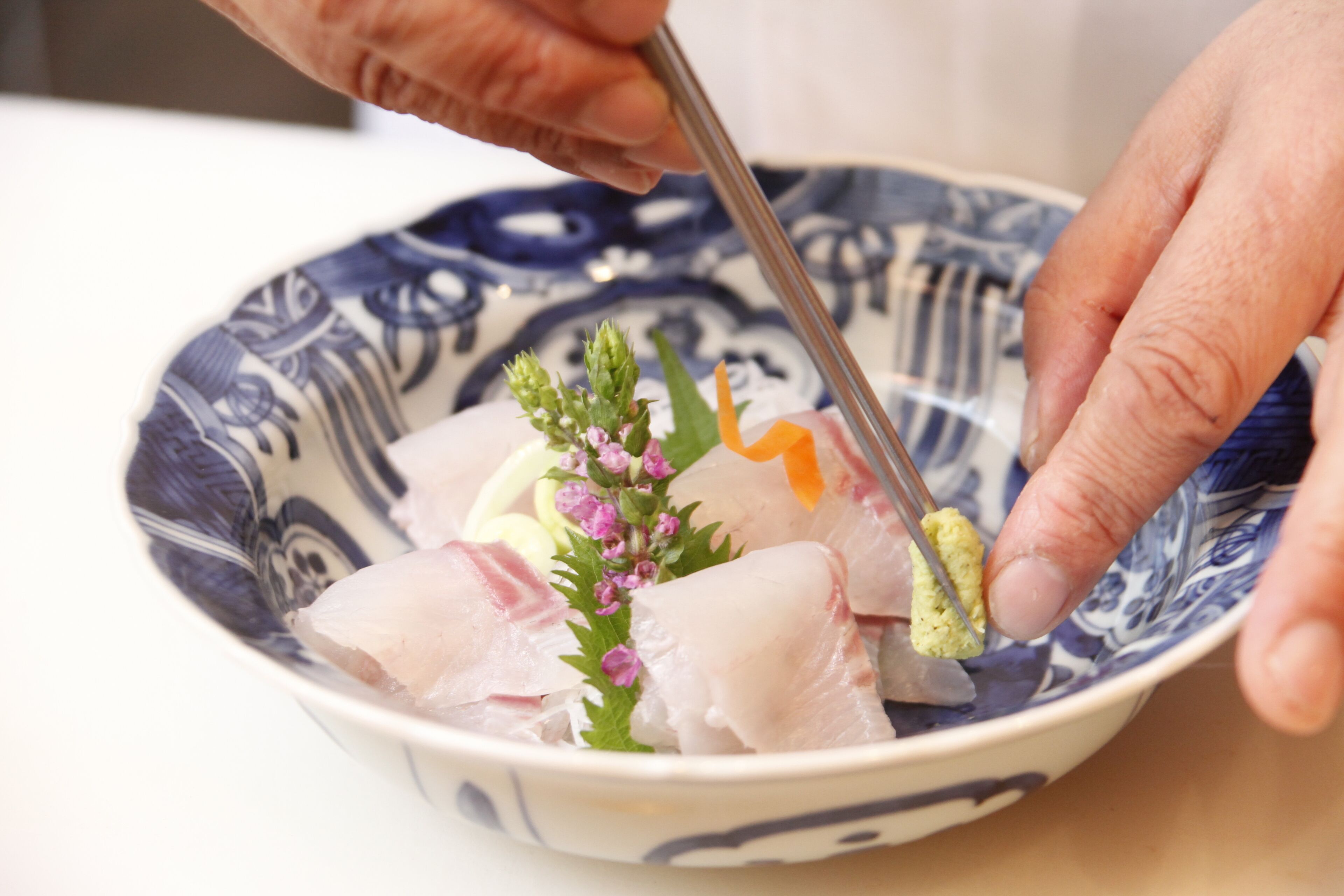 A bowl of sashimi with chopsticks.