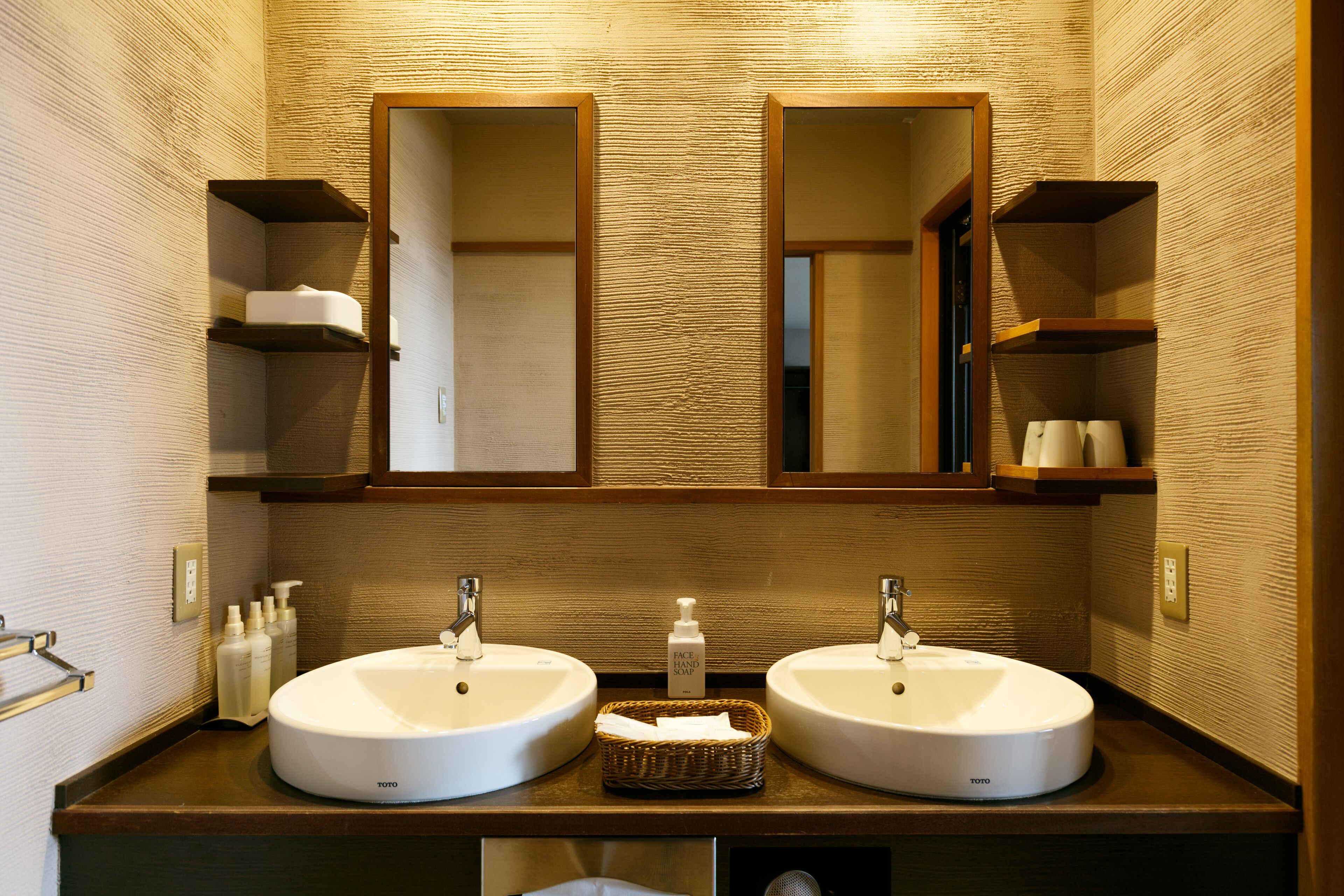 Une salle de bain avec deux lavabos, un miroir et des étagères contenant des articles de toilette.