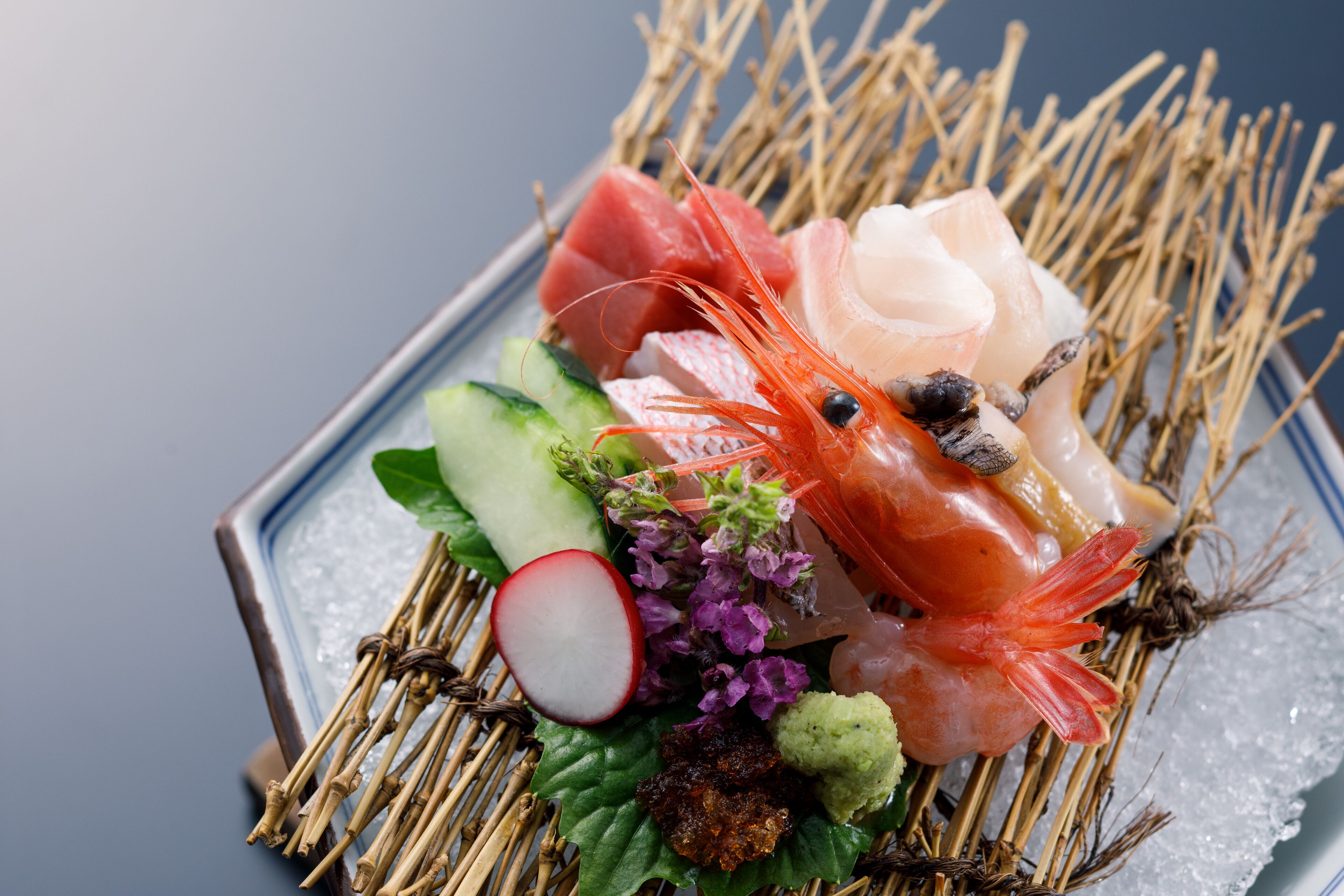 A sushi platter with various types of fish and vegetables on ice.